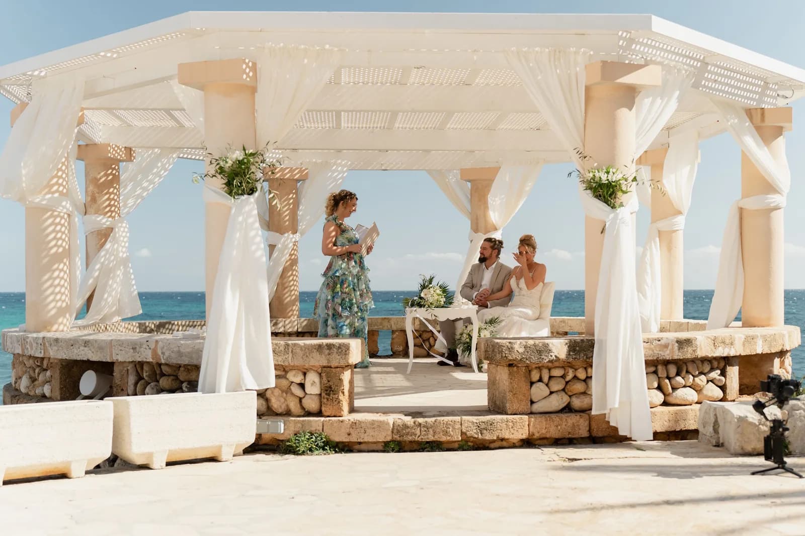 Ein Brautpaar feiert sein Ja-Wort unter einem hellen Pavillon am Meer